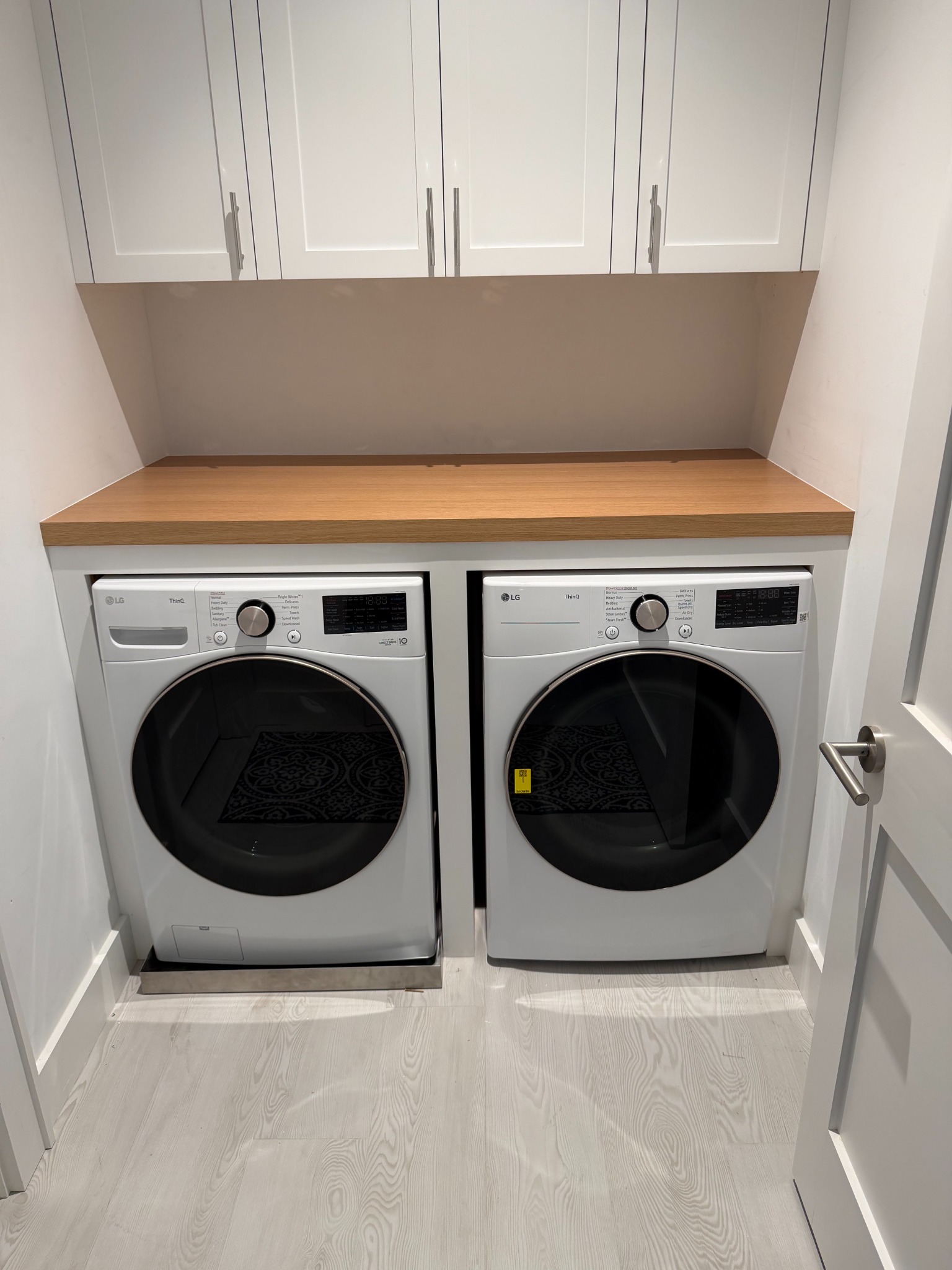Basement laundry cabinetry with natural wood counter and painted upper cabinets