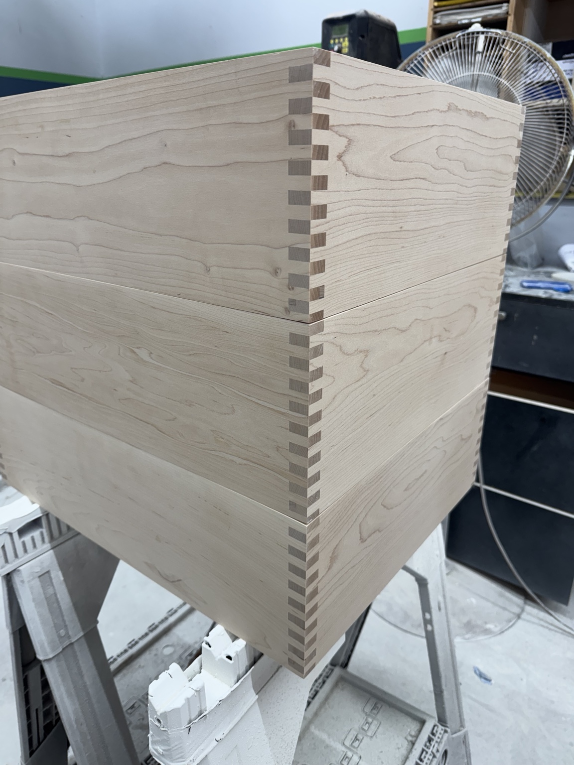 Close-up of precisely fitted wooden drawer joinery and continuous wood grain in the Maidstone workshop