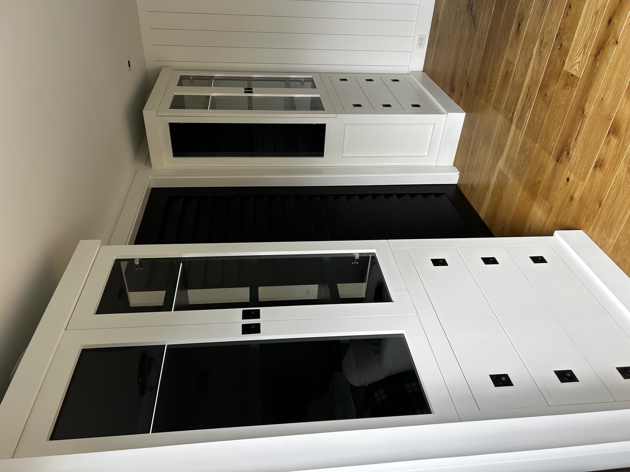 Custom painted storage wall with black interiors, glass doors, drawers, and integrated lighting