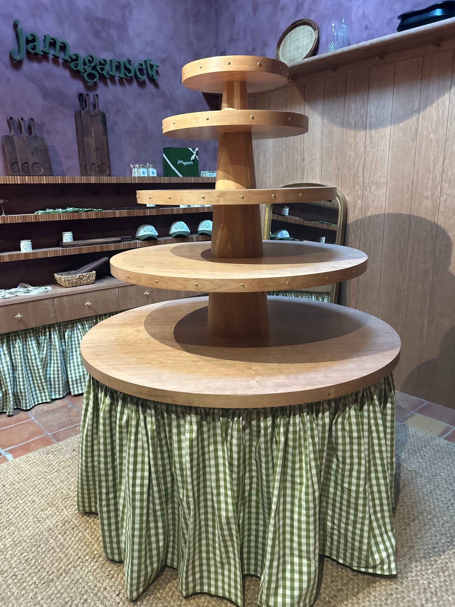 Tiered round cherry display table with a skirted base in the completed retail space