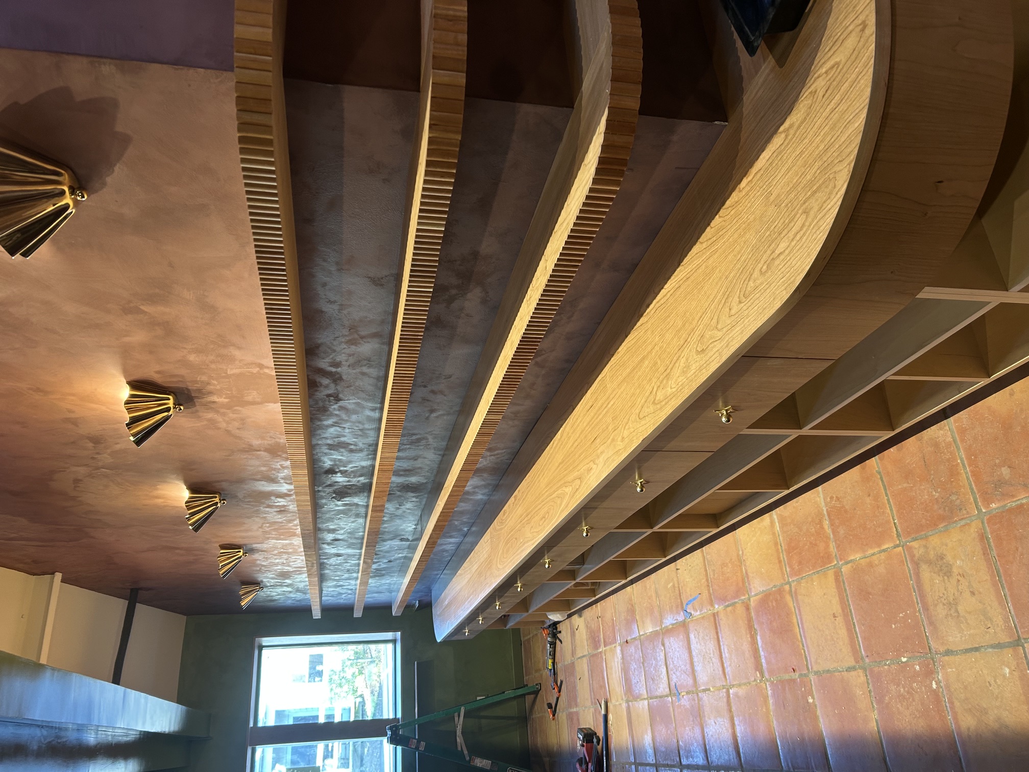 Full cherry retail shelving run with brass gallery rails and curved end cabinetry