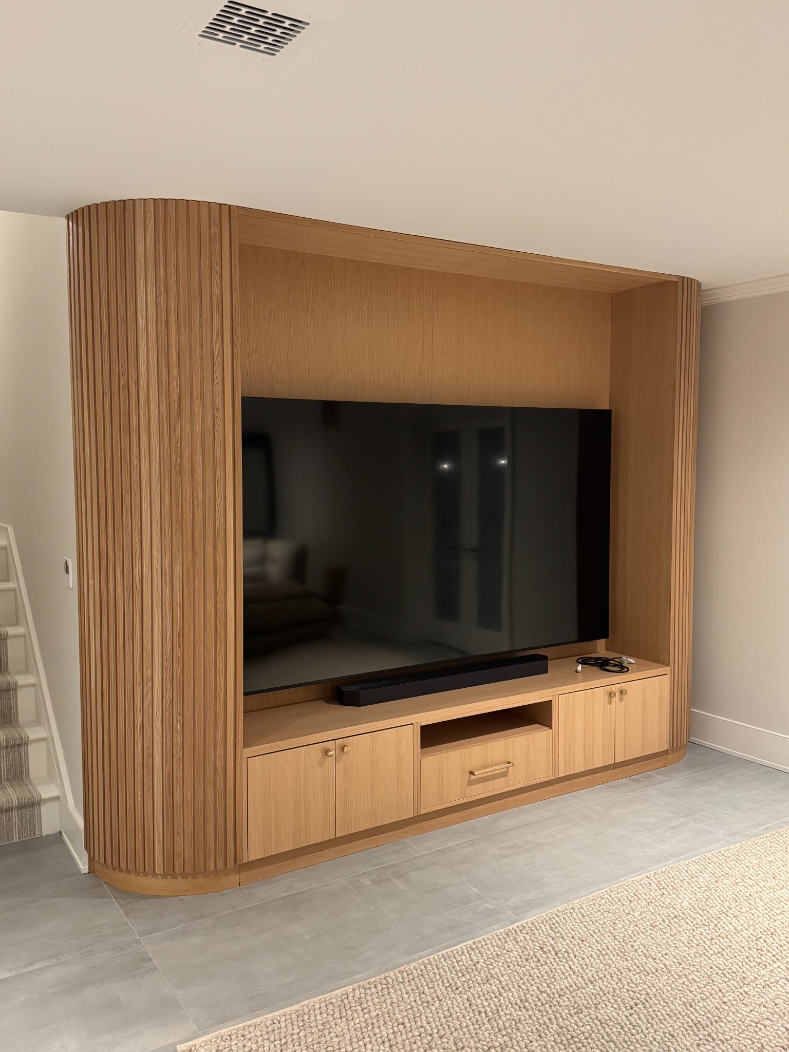 White oak entertainment wall with curved reeded sides and integrated television cabinetry
