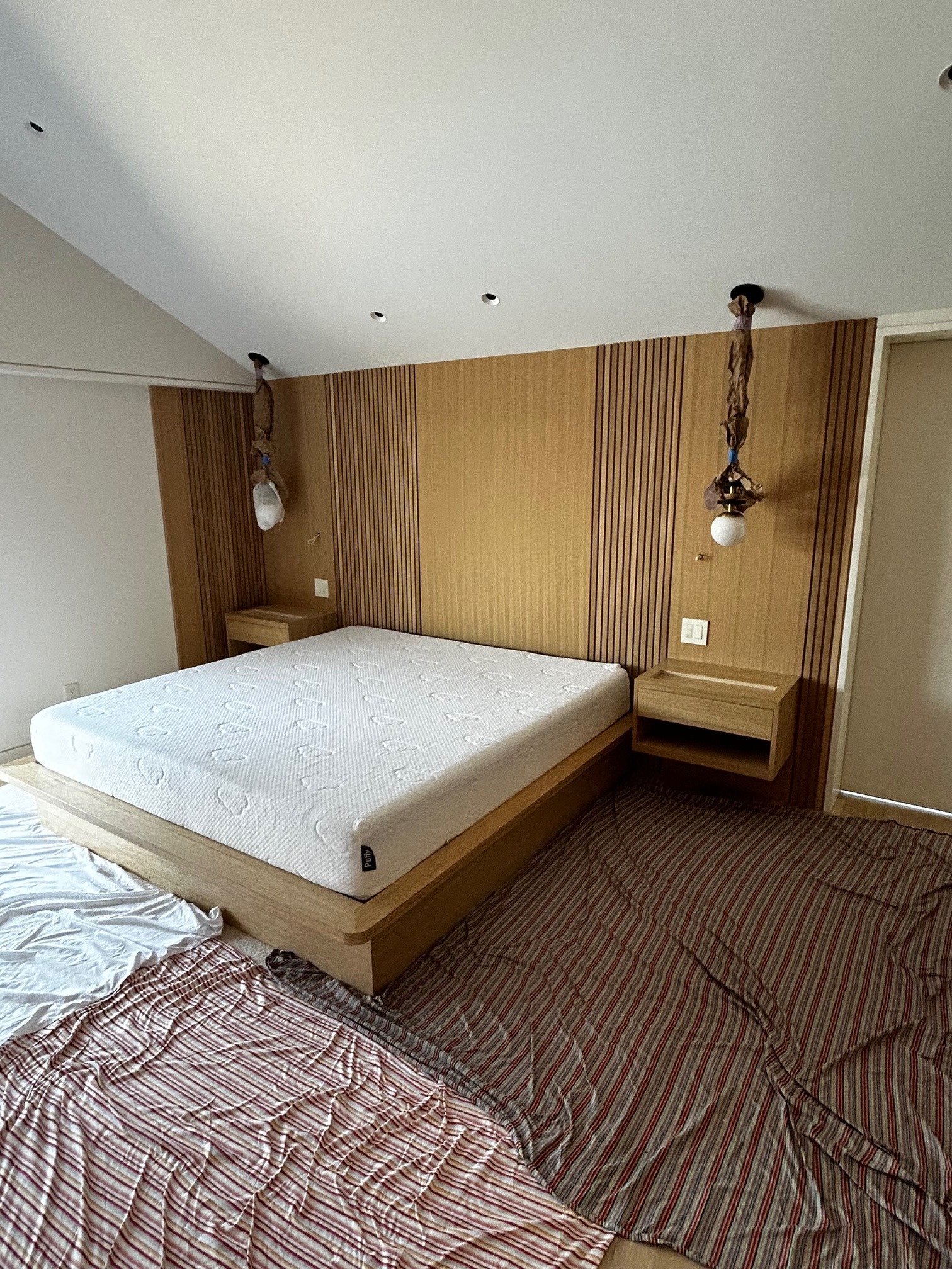 Custom white oak bed integrated into a fluted headboard wall with matching floating nightstands