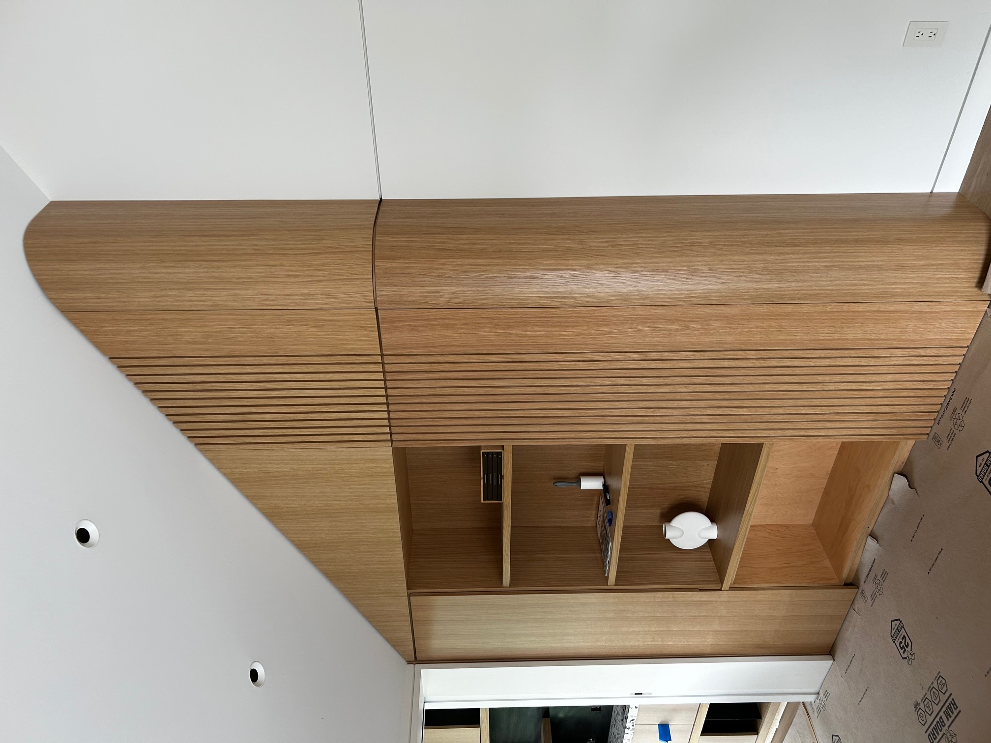 White oak wardrobe integrated beneath a sloped ceiling with curved fluted end panel