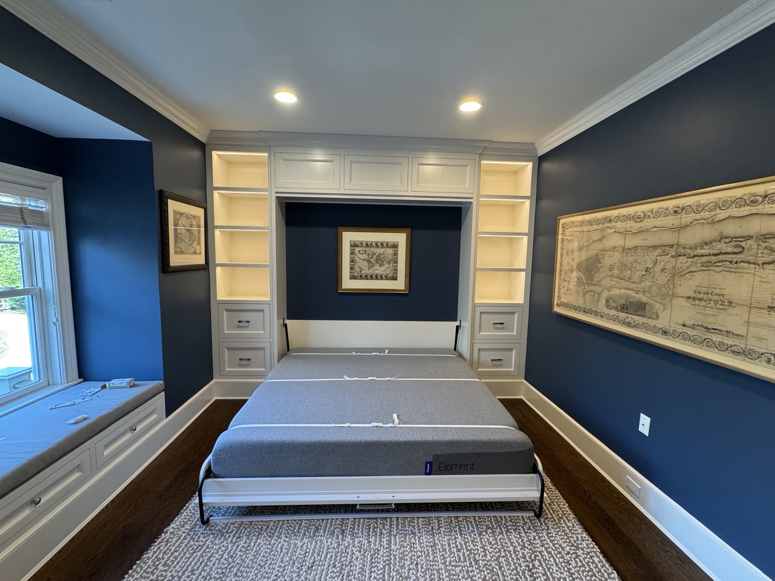 Completed Watermill Murphy bed open with illuminated shelving and adjacent window-seat storage