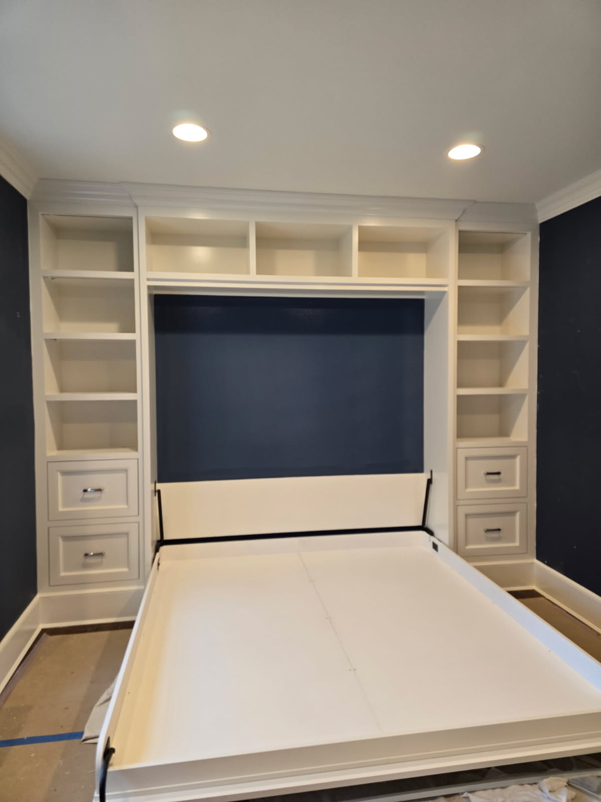 Custom Murphy bed open beneath the painted shelving surround