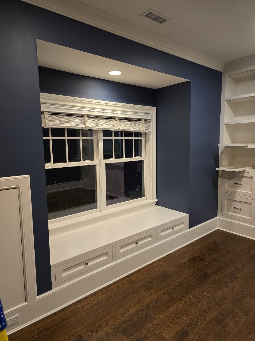 Painted window seat with fitted storage drawers beneath a recessed window